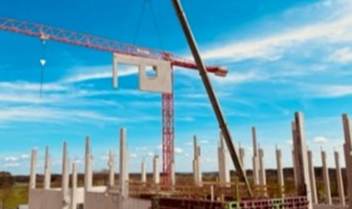 Kran hebt Betonfertigteil am FEGA & Schmitt Neubau
